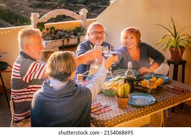 Mature Adult Friends Enjoy Clinking With Wine At The Table. Happy Retired People Have Fun Toasting With Glasses. Retired Men And Women Celebrate And Laughing A Lot. Elderly Pensioner Lifestyle