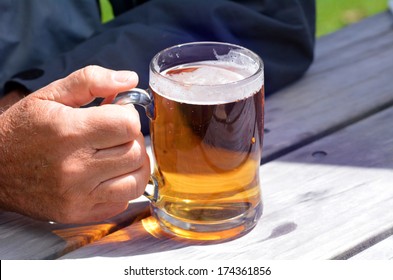 Mature Adult Man Hand Holding A Mug Of Beer. Copy Space