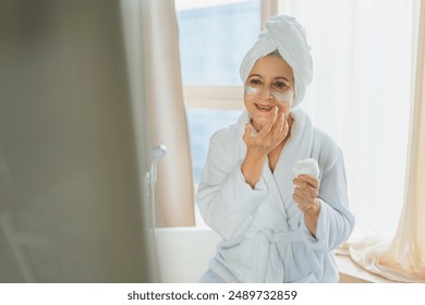 Mature adult old woman applying nourishing anti age face cream doing daily beauty routine. Senior woman with white mask or creme on skin gets facial treatment Skin care aging beauty skincare cosmetics - Powered by Shutterstock