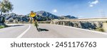 Mature Adult on a racing bike climbing the hill at mediterranean sea landscape coastal mountain road - mallorca mountains