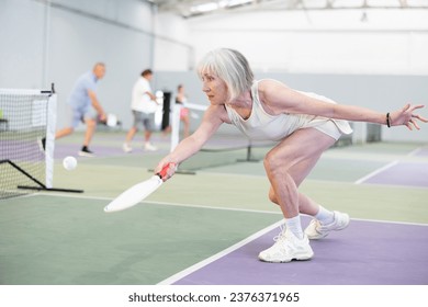 Mature adult woman playing doubles pickleball game, healthy lifestyle concept - Powered by Shutterstock