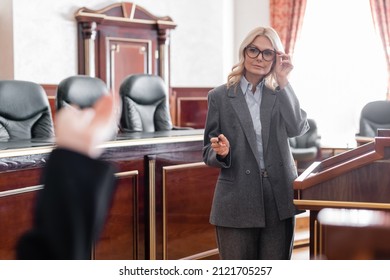 Mature Advocate Pointing With Hand And Adjusting Eyeglasses During Questioning Of Witness In Court