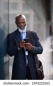 Mature african american businessman using smartphone in city texting on mobile phone