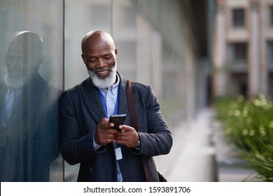 Mature african american businessman using smartphone in city texting on mobile phone
