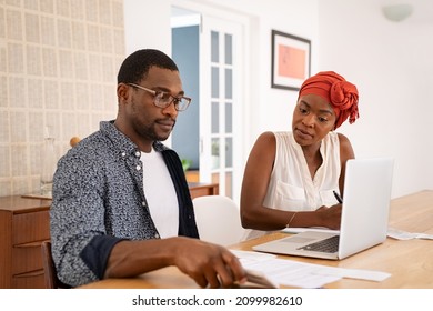 Mature African American Couple Discussing Home Finance With Bank Statement And Laptop. Black Man And Serious Woman Managing Budget And Checking Accountancy And Bills. Couple Working And Writing Notes.