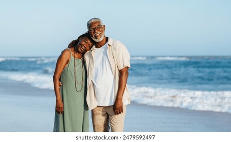 A mature African American couple shares a happy moment together while walking along a sunny beach. They exude warmth and companionship, perfectly capturing a serene day by the sea. - Powered by Shutterstock