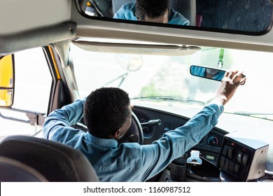 Mature African American Driver Adjusting Back View Mirror At Bus