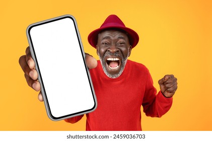 Mature African American man wearing a red sweater is holding a cell phone in his hand. He is focused on the screen, possibly texting or browsing. The background is simple and nondescript. - Powered by Shutterstock