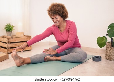 Mature african woman doing yoga stretching exercise at home - Healthy lifestyle and sport concept - Powered by Shutterstock