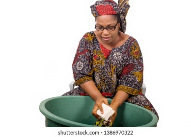 Mature African Woman In Loincloth Sitting Doing Laundry.