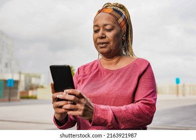 Mature african woman using mobile phone after sport workout in the city