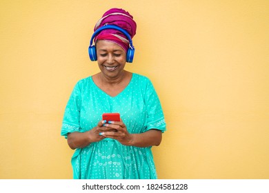 Mature african woman using smartphone app for creating playlist music - Focus on face