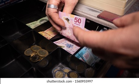 Mature age woman accommodates money at the cash register, Mexican pesos