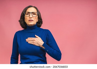 Mature Aged Senior Old Beautiful Caucasian Woman Wearing Casual Suffering From Heart Pain, Touching Chest, Closed Eyes. Copy Space. Isolated Over Pink Background.