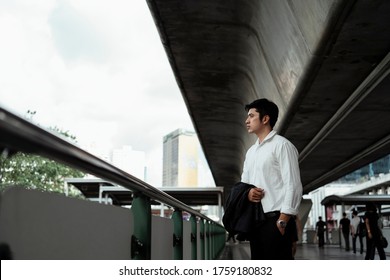 Mature Asian Business Man On White Formal Shirt Standing Alone On Walkway Looking Down The Road.