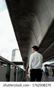 Mature Asian Business Man On White Formal Shirt Walking On Walkway Looking Down The Road.