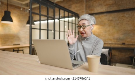 Mature Asian Business Woman Wears Glasses Using Laptop Computer Sit At Workplace Desk. Video Conference, Online Meeting Video Call, Virtual Meeting