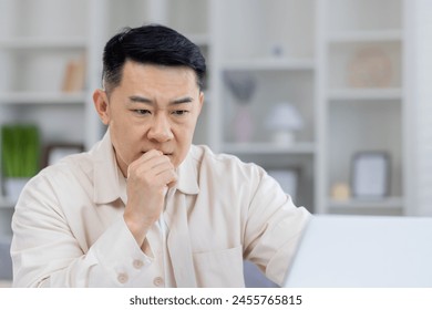 Mature Asian businessman in thoughtful pose, sitting at his office desk. This image captures a moment of deep concentration and decision-making in a professional setting. - Powered by Shutterstock