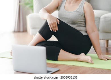 Mature Asian Chubby Fat Woman Sitting On The Floor In Living Room Practice Online Yoga Lesson With The Computer. Female Having Meditate Training Class On The Laptop.
