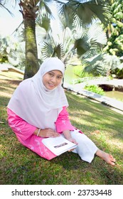 Mature Asian Malay Muslim Woman Reading, In An Outdoor Park