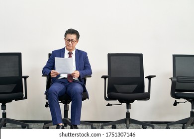 Mature Asian Male Job Seeker Preparing For Interview While Waiting In Line