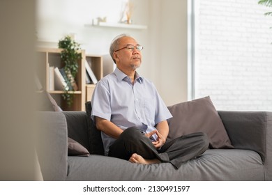 Mature Asian man doing yoga for meditation on yoga mat in living room at home.Clam of senior or elderly men meditation deep breath and relax at cozy home.Happy Retired Meditation at home concept  - Powered by Shutterstock