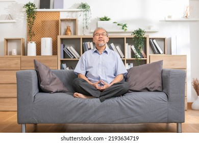 Mature Asian Man Doing Yoga For Meditation On Yoga Mat In Living Room At Home.Clam Of Senior Or Elderly Men Meditation Deep Breath And Relax At Cozy Home.Happy Retired Meditation At Home Concept 