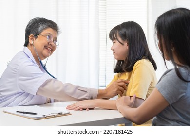 Mature Asian Physician Psychiatrist, General Woman Doctor Consulting Concerned With Teenage Girl, Child Patient, Using Stethoscope To Listen, Appointment At Clinic. Health Care, Check Up Medical.