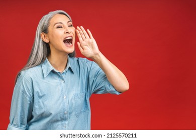 Mature Asian Senior Surprised Woman 50s Wears Screaming Announces Discounts Sale Hurry Up Isolated Over Red Background Studio Portrait. People Lifestyle Concept.