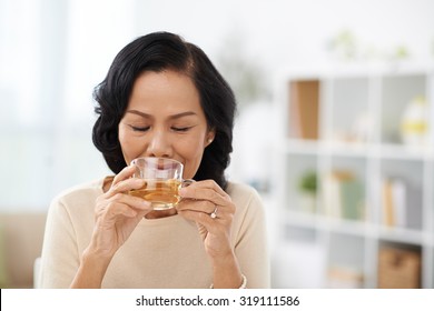 Mature Asian Woman Drinking Hot Herbal Tea