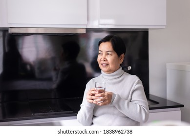 Mature Asian Woman Drinking Water At Home In The Morning,Happy And Smiling,Elderly Healthy Care Concept