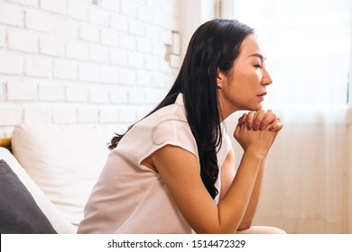 Mature Asian woman putting two hands together and praying at home. Joined and Clasped Hands. Spirituality and Religion concept
