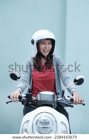 mature asian woman showing excited expression while riding motorcycle