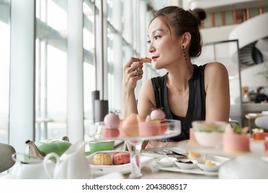 Mature Asian Woman Sitting At Table Eating Dessert Alone In Hotel Lobby Coffee Shop