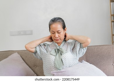 Mature Asian Woman Suffering From Neck Pain, Sitting On Couch.