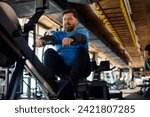 Mature athlete using rowing machine while working out in a gym.
