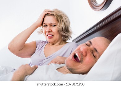 Mature aweary woman disturbed with partner snores continiously - Powered by Shutterstock