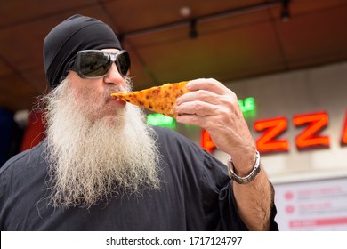 Mature Bearded Man Eating New York Style Pepperoni Pizza Outdoors