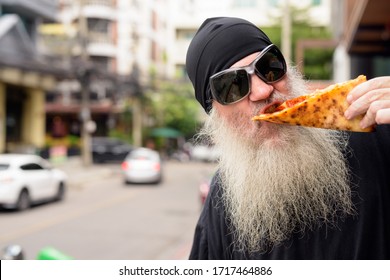 Mature Bearded Man Eating New York Style Pepperoni Pizza Outdoors