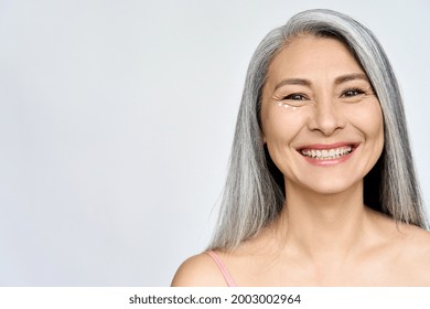 Mature Beautiful Middle Aged Asian Woman, Senior Older Grey Haired Lady Looking At Camera Smiling Applying Under Eye Antiaging Anti Wrinkle Perfect Skin Care Cream, Isolated On White Headshot.