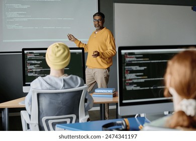 Mature biracial man wearing smart casual clothes teaching coding in modern classroom equipped with computers - Powered by Shutterstock