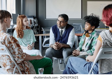 Mature biracial school psychologist talking to group of ethnically diverse teenagers during therapy session - Powered by Shutterstock