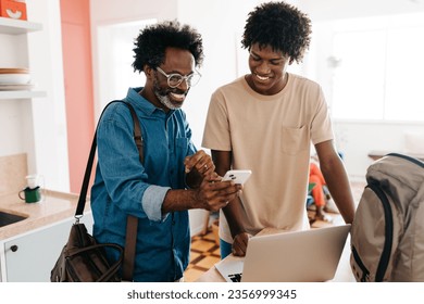 Mature black father and his teenage son, both with afro hairstyles, bond during their morning routine at home. Father using a smartphone with his son as they prepare for the day ahead.  - Powered by Shutterstock