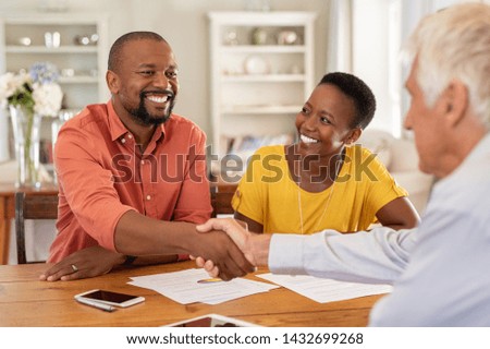 Mature black husband shaking hands with senior agent on taking loan. Happy african couple sealing with handshake a contract with financial advisor for investment. Man making sale purchase deal.