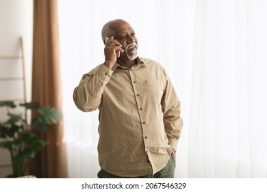 Mature Black Man Talking On Smartphone Looking Aside Standing Indoors Working From Home. Senior Male Having Pleasant Phone Conversation. Gadgets, Mobile Communication - Powered by Shutterstock