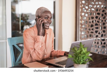 Mature Black Woman Working With Laptop Outdoor While Talking On Smartphone Call