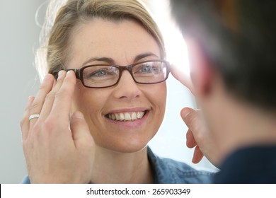 Mature blond woman with optician trying eyeglasses  - Powered by Shutterstock