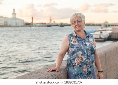 Mature blonde short haired woman in linen clothes on Neva River embankment