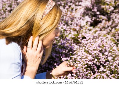 Mature Blonde Woman Smelling Flowers