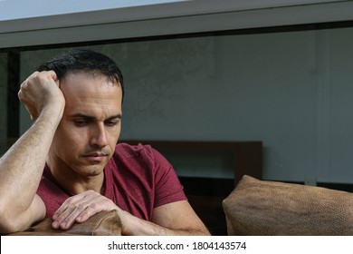 Mature Brazilian Man (44 Years Old) Sitting On The Brown Sofa, Behind The Glass, Sad And Crestfallen.